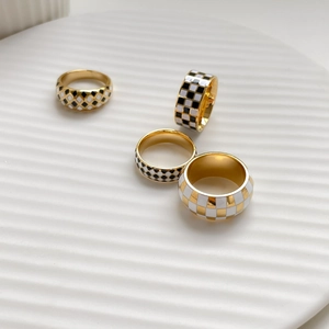 Vintage gold checkered rings set with black and white enamel grid patterns on white plate