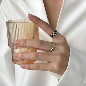Modern black and white checkerboard rings with gold edges worn on model's hand