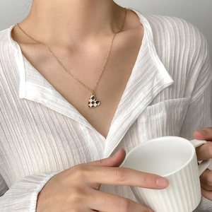 Golden heart necklace with black and white checkerboard pattern on a model