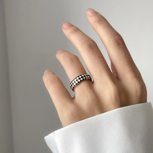Detailed view of checkered enamel ring with black and white patterns on golden band