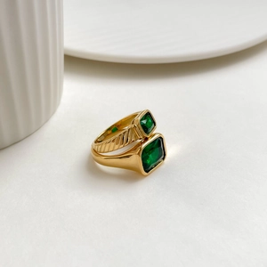 Set of gold rings featuring rectangular emerald-cut green gemstones on a white background