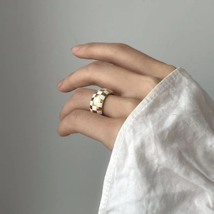 Close-up of retro black and white checkerboard ring with gold finish on a model's hand