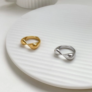 Macro detail of chunky gold and silver teardrop rings on a white textured dish