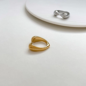 Detail shot of chunky heart knot rings in gold and silver finish on white ceramic plate