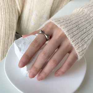 Detailed view of silver twisted heart ring with a polished finish worn on finger