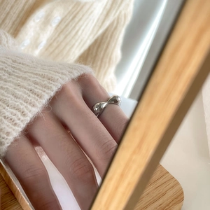 Close-up of minimalist silver fluid ring with irregular mirror finish on a finger