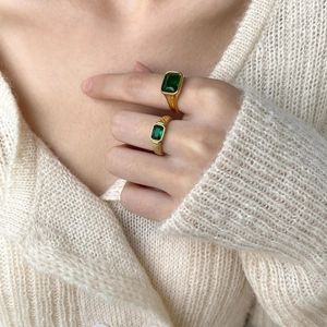 Minimalist gold plated rings set with rectangular emerald green zircon stones on model