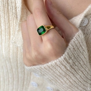 Close-up of elegant emerald-cut green gemstone on polished gold band worn by a model