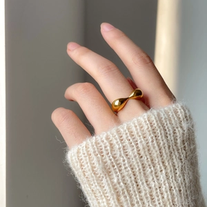 Close-up of a minimalist chunky golden heart ring worn with a soft knit sweater