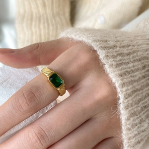 Detail of vintage gold ring with emerald cut green zircon shown on finger