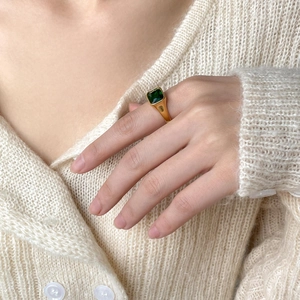 Close-up of square emerald green zircon ring with gold band on hand in warm natural light