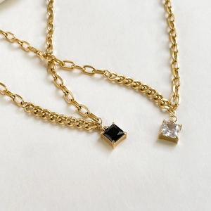 Golden necklace set with square black and white zircon pendants on a white background