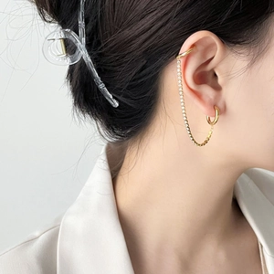 Detail of double piercing gold hoop earring with pavé zircon chain and ear cuff