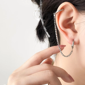 Macro detail of silver double-piercing earrings with sleek cubic chain and hoop design