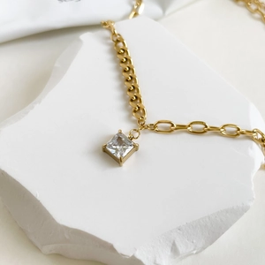 Detailed macro view of square zircon pendant with mixed Cuban and oval link chains