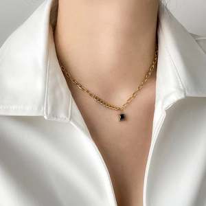 Detail of square black zircon pendant necklace with gold chain on model's neck