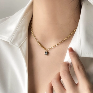 Elegant gold necklace with a square black zircon pendant worn on a female neck