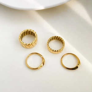 Set of four gold geometric rings with textured thread patterns and irregular fluid shapes