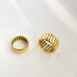Close-up of golden geometric rings with 3D ribbed textures and polished inner grooves