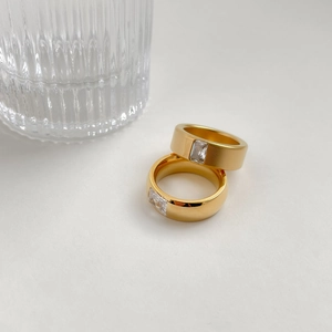 Gold plated titanium rings with matte finish and square zircon stones on white background
