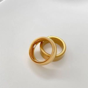 Detailed view of two gold-plated smart rings with integrated sensors on white background