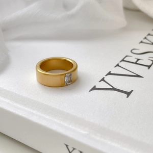 Macro shot of matte gold titanium ring featuring a rectangular zircon on a white background