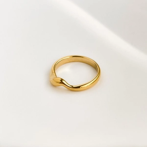 Detailed close-up of a polished gold geometric twisted ring with smooth wave texture