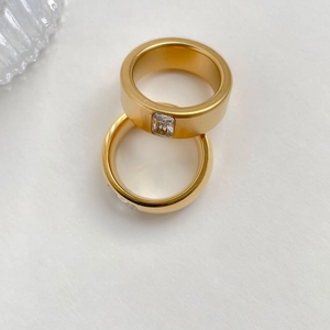 Frosted gold titanium steel ring set with square zircon on white textured background
