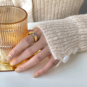 Detail of wide gold-plated steel ring featuring a rectangle zircon on finger