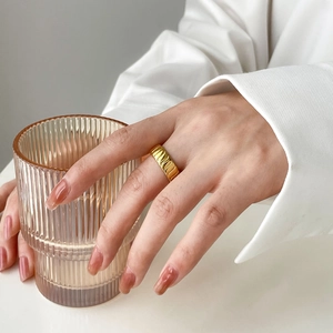 Detailed view of a gold-plated twisted geometric ring with wavy pleated texture on a model