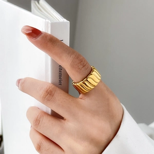 Close-up of a wide gold twisted croissant ring showing metallic texture and wave design