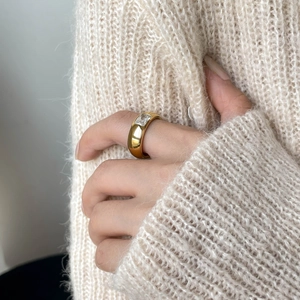 Detailed view of wide gold plated ring with rectangular zircon on finger with sweater