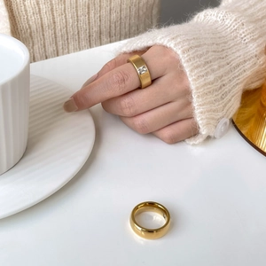 Detail of gold-plated titanium rings featuring a rectangular zircon and smooth finish
