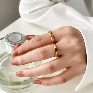 Detail of stacked gold geometric twisted rings with polished finish on model's hand