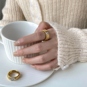 Detail of gold plated matte ring featuring a single rectangular zircon stone on finger