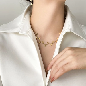 Elegant gold leaf necklace and earrings set styled on a model wearing a white shirt