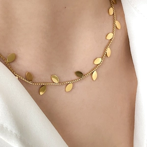 Close-up of elegant gold box chain necklace featuring polished olive leaf metal charms