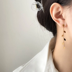 Elegant gold leaf tassel earrings featured on model, stylish long pendant jewelry