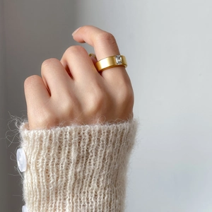Gold plated matte titanium ring with rectangular zircon worn on a model's finger