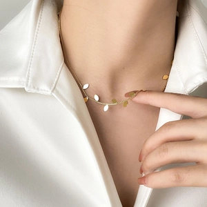 Close-up of golden leaf pendant necklace on woman wearing a white professional shirt