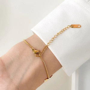 Close-up of 18K gold leaf bracelet with adjustable lobster clasp on wrist sleeve