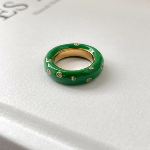 Détail d'une bague en émail vert avec cristaux incrustés sur fond papier blanc
