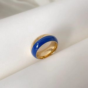 Détail d'une bague dôme dorée avec bande en émail bleu profond et fini poli