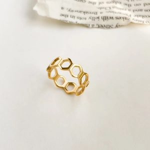 Vue détaillée du motif alvéolé doré en forme d'hexagone sur une bague minimaliste