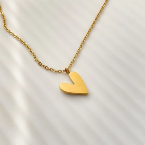 Macro shot of minimalist gold-plated heart pendant on a delicate cross-link chain necklace
