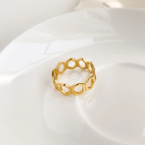 Détail macro d'une bague nid d'abeille dorée sur une assiette en céramique blanche