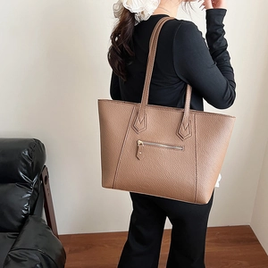 Brown pebbled leather tote bag with gold hardware worn by a model for a chic look