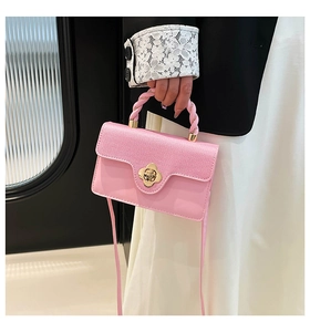 Close-up of pink mini bag with gold flower twist lock and twisted top handle