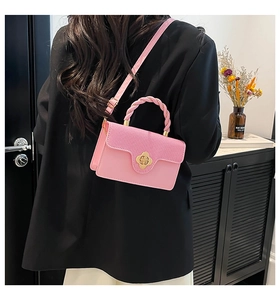 Pink crossbody bag with woven handle and gold clover clasp shown on model