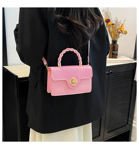 Pink shoulder bag with flower buckle and braided handle paired with a black blazer